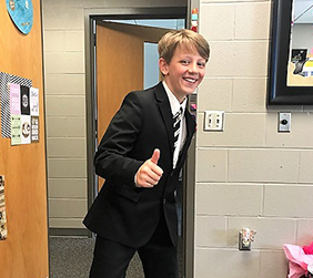Student wearing formal attire gives a thumbs up
